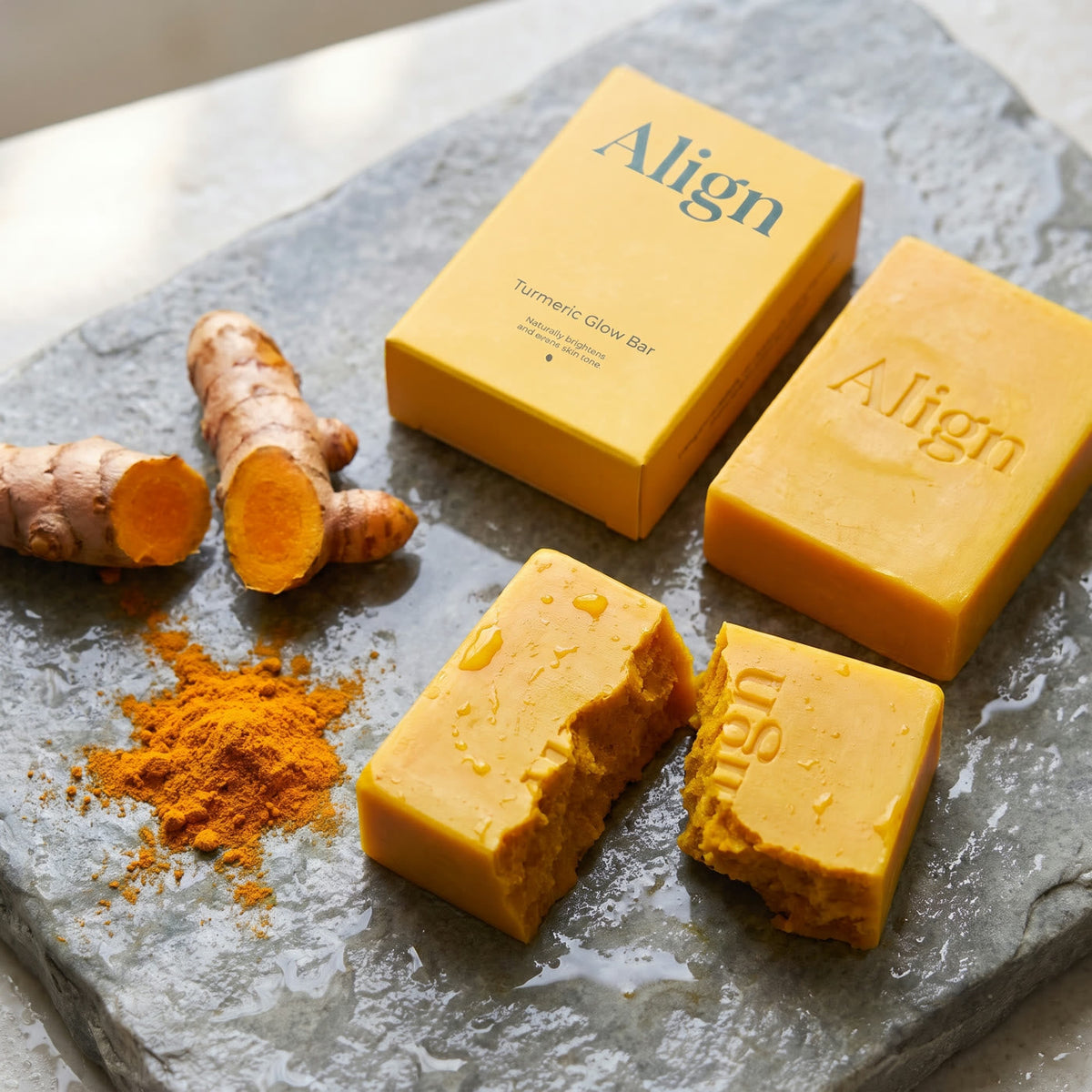 Turmeric Glow Bar broken in half next to fresh turmeric root and powder